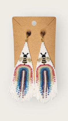 the beaded bird earrings in white and multicolors are hanging from a card