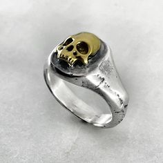 Embrace the macabre with our 925 Sterling Silver Signet Ring featuring a hauntingly beautiful melted gold skull design. This unique piece is a symphony of darkness and luxury, meticulously crafted to stand out. Channel your inner mystique with this statement ring that transcends conventional styles. Immerse yourself in the allure of the macabre. Solid oxidised 925 sterling silver signet ring featuring a melted gold skull design. Top of ring measures 1.3cm x 1.3cm Material : 925 Oxidised Sterling Silver, 24k Gold Plate. Each piece is handmade to order in the Jewel Thief Brighton atelier. Melted Gold, Jewelry Mood Board, Tooth Ring, Fancy Things, Gold Skull, Hauntingly Beautiful, Silver Signet Ring, Rings Cool, Skull Ring