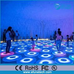 people are dancing on an interactive floor in a room with blue and pink circles,