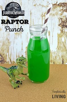 a green drink in a mason jar with a dinosaur toy next to it and the caption raptor punch