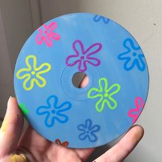 a hand holding a blue disc with flowers painted on it