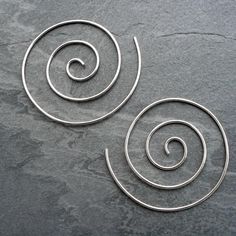 two silver spirals on a gray stone surface, with one curled in the middle