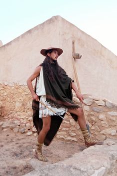 a man with long hair wearing a hat and holding a stick