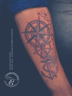 a person with a compass tattoo on their arm and the other hand is holding an anchor