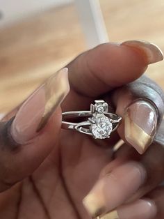 a close up of a person's hand holding a ring with a diamond on it