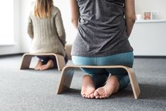 two women sitting on the floor with their feet up and one standing in front of them