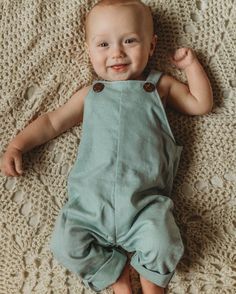 a smiling baby laying on top of a blanket