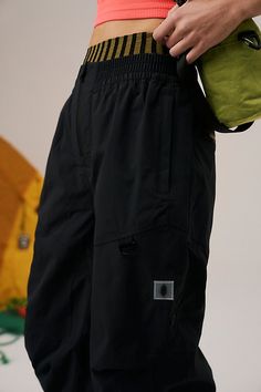 Suit up for wet weather in these packable rain pants, featuring a durable, waterproof nylon fabrication and roomy relaxed fit perfect for layering. **Fit:** Relaxed, high-waisted **Features:** 100% Nylon fabrication; durable; waterproof; fully mesh-lined; elasticated waistband; zipper opening; elasticated cuffs are Velcro adjustable; zippered hand pockets; zipper at lower leg for adjustability; snap openings at back for ventilation **Why We | Singin In The Rain Packable Pants by FP Movement at F Functional Wide Leg Parachute Pants For Outdoor, Functional Wide-leg Parachute Pants For Outdoor, Black Nylon Parachute Pants With Functional Pockets, Black Waterproof Techwear Parachute Pants, Functional Black Waterproof Pants, Black Waterproof Techwear Pants, Urban Nylon Parachute Pants For Outdoor, Winter Utility Nylon Parachute Pants, Black Utility Parachute Pants For Hiking