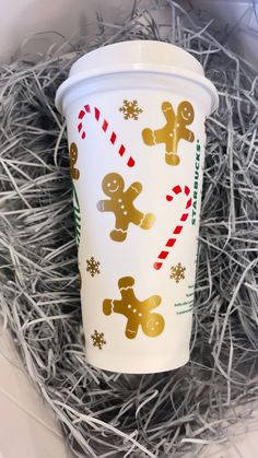 a white cup with gold foiled gingerbreads and candy canes on it