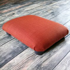 an orange cushion sitting on top of a wooden floor