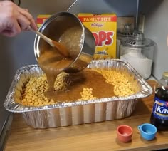 a person pouring batter into a tin pan filled with corn kernels and other ingredients