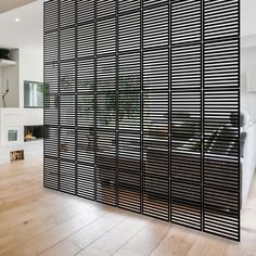 the room divider is made out of black slatted wood and has an open fireplace