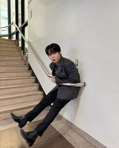 a man sitting on top of a stair case next to a set of stairs with his legs crossed