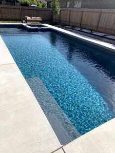 an empty swimming pool in a backyard with no people around it and a wooden fence behind it