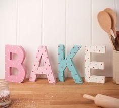 the word bake spelled with wooden letters and spoons next to it on a table