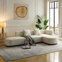 a living room with a large white sectional couch and potted plant in the corner