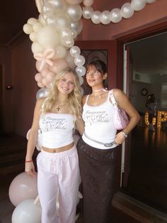 two women standing next to each other in front of balloons