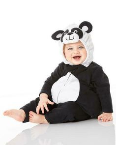 a baby in a panda costume sitting on the floor with his feet up and smiling