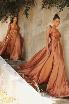 two women in long dresses are standing on some steps and one woman is wearing an orange dress