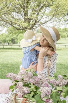 a woman holding a small child in her arms while sitting on a table with flowers