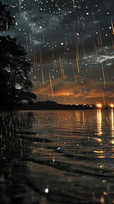 the sky is filled with stars and rain as it reflects in the water at night