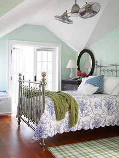 a bedroom with green and white walls, wood flooring and a metal bed frame