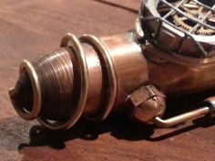 a metal object sitting on top of a wooden table next to a clock face and gears