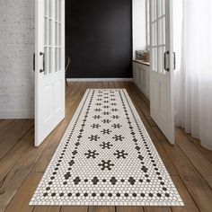 a white and black rug on top of a wooden floor next to an open door