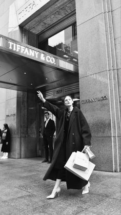 a woman is walking down the street with her arms in the air and holding shopping bags