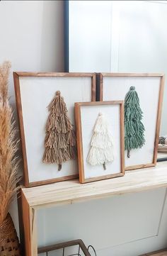 three framed christmas trees sitting on top of a wooden table