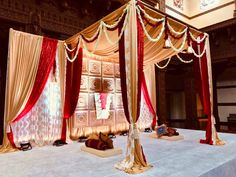 an elaborate canopy bed with red and gold drapes