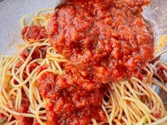 spaghetti with sauce being stirred over it in a bowl