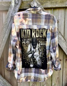 This is a one of a kind KID ROCK plaid flannel shirt.  This size Xlarge flannel shirt has two pockets on the front, buttons up and is long sleeve. On the back of the flannel there's a original Kid Rock tee that has been sewn into it. The flannel has been frayed trimming around the tee. This shirt has been bleached which gives it an overall distressed vintage style look.  All my shirts are ONE OF A KIND. They are all upcycled by being previously owned so there will be signs of wear and tear. This Distressed Button-up Shirt For Fall, Distressed Long Sleeve Shirt For Fall, Flannel Shirt For Streetwear In Fall, Fall Graphic Print Long Sleeve Flannel Shirt, Fall Long Sleeve Flannel Shirt With Graphic Print, Fall Flannel Shirt With Graphic Print, Fall Graphic Print Flannel Shirt, Grunge Cotton Flannel Shirt For Fall, Plaid Flannel Grunge Shirt