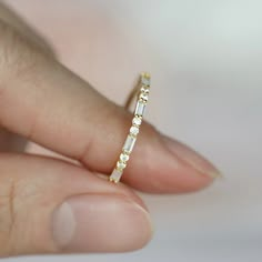 a woman's hand holding a yellow and white diamond wedding band in her left hand