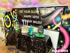 a birthday party with balloons, streamers and cake on a table that says get your glow one happy 10th birthday miles