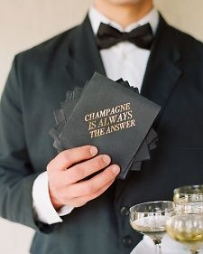 a man in a tuxedo is holding two cards that say champagne is always the answer