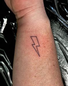 a small black lightning tattoo on the left arm and right arm, it looks like there is a bolt in the middle