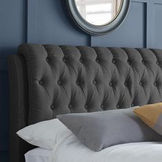 a bed that has some pillows on it and a round mirror above the headboard