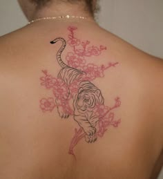 a woman's back with a tiger and flowers tattoo on her left side shoulder