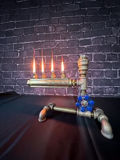 a lit candle is sitting on top of a pipe that has been placed in front of a brick wall