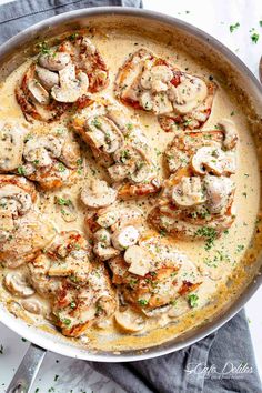 a skillet filled with chicken and mushrooms covered in gravy, garnished with parsley