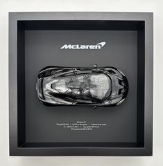 a black and white photo of a sports car in a shadow box with the word mclaren on it