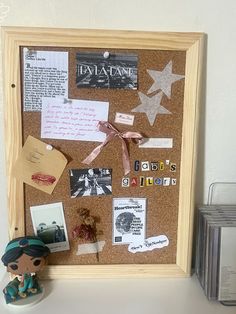 a cork board with pictures and magnets attached to it next to a small figurine