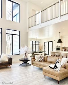 a living room filled with furniture and windows next to a staircase leading up to a second story