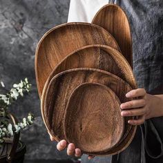 a person holding three wooden plates in their hands