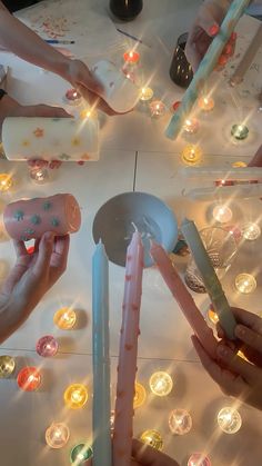 several people are lighting candles on a table with many small lights around them and one person is holding a candle in the middle