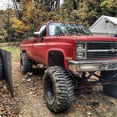 an old red truck parked in the woods