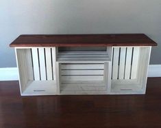 a white wooden entertainment center with two doors and shelves on the top, sitting on a hard wood floor