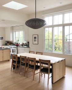 a dining room table and chairs in front of two large windows with lots of natural light