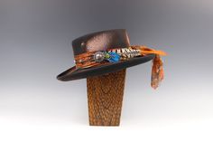 The Havana Gambler Hat Another stunning limited edition gambler hat from the Vera Black Studio. Featuring a silk paisley fabric hat band. We have then layered our signature faux suede strap over the top and detailed it with lapis and tiger eye stone pendants. On the left side of the hat we have used a brushed silver & gold concho, detailing with a combination of red tail pheasant and dyed ostrich feathers. On the right hand side we have added our silver 'VB' pirate coin. Trailing at the back Festival Top Hat With Short Brim, Pirate Coins, Gambler Hat, Black Studio, Finger Bracelets, Hair Braider, Feather Hair Clips, Golden Leaf, Large Hats